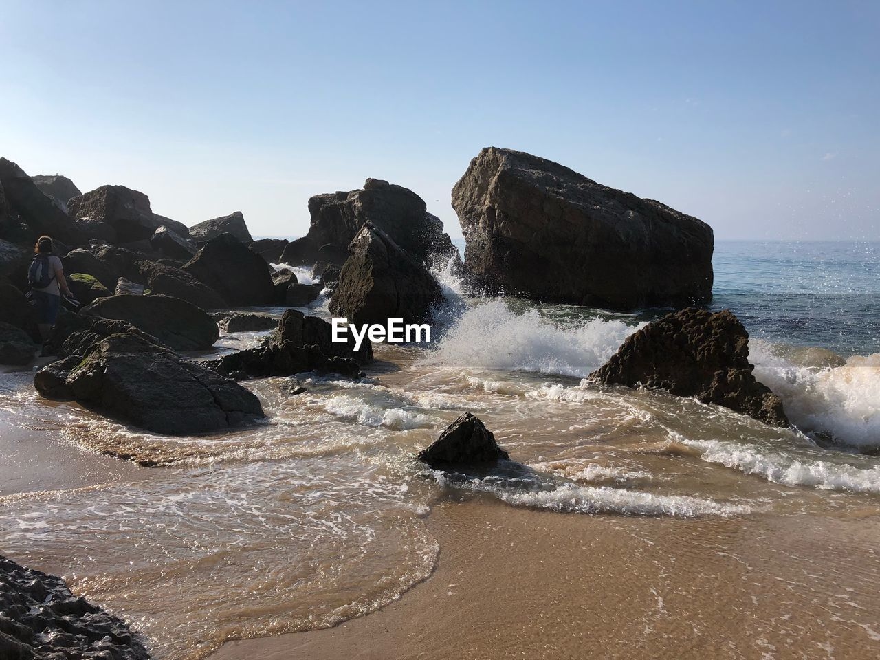 ROCKS ON BEACH AGAINST CLEAR SKY