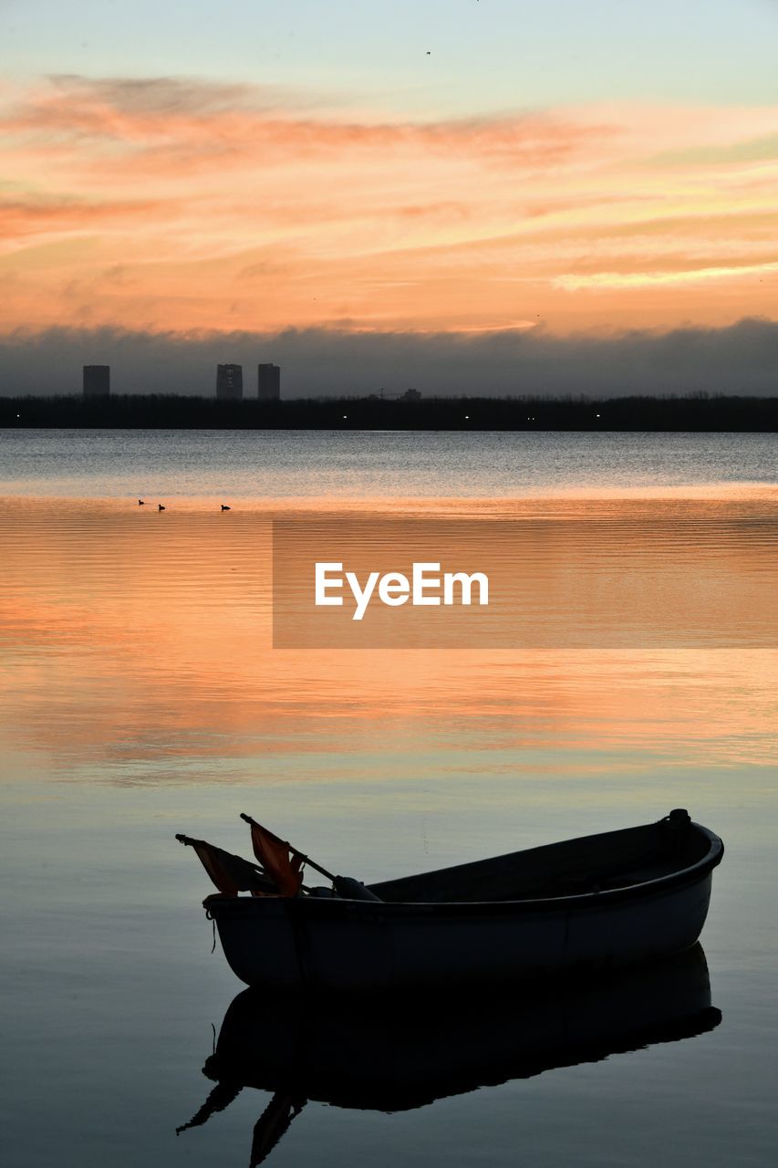 Boat moored on sea against sky during sunset