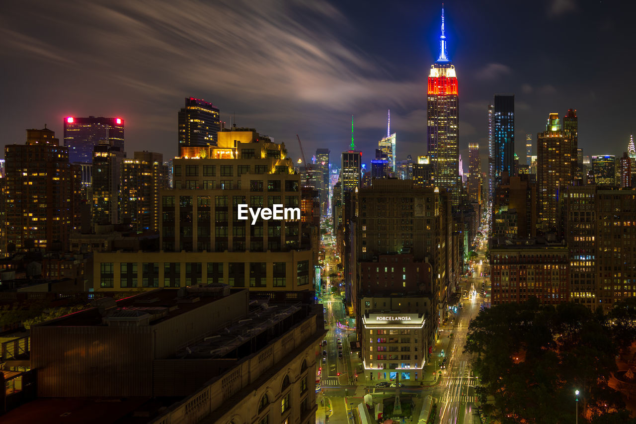 Illuminated empire state building amidst cityscape at night