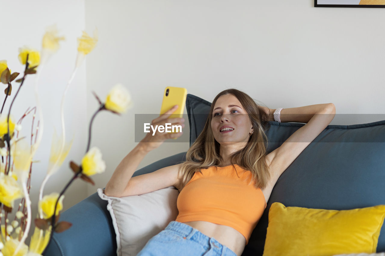 young woman using mobile phone while sitting at home