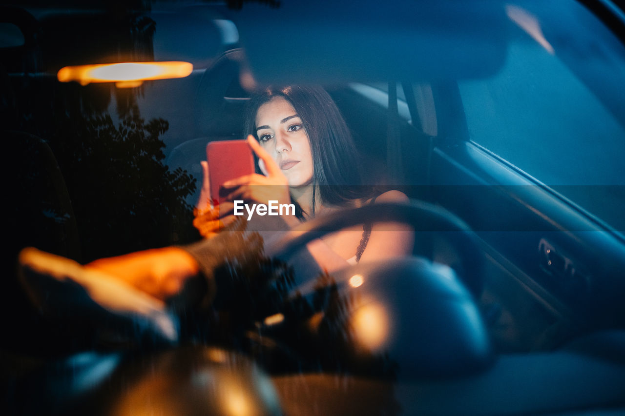 Young woman using smart phone while sitting in car