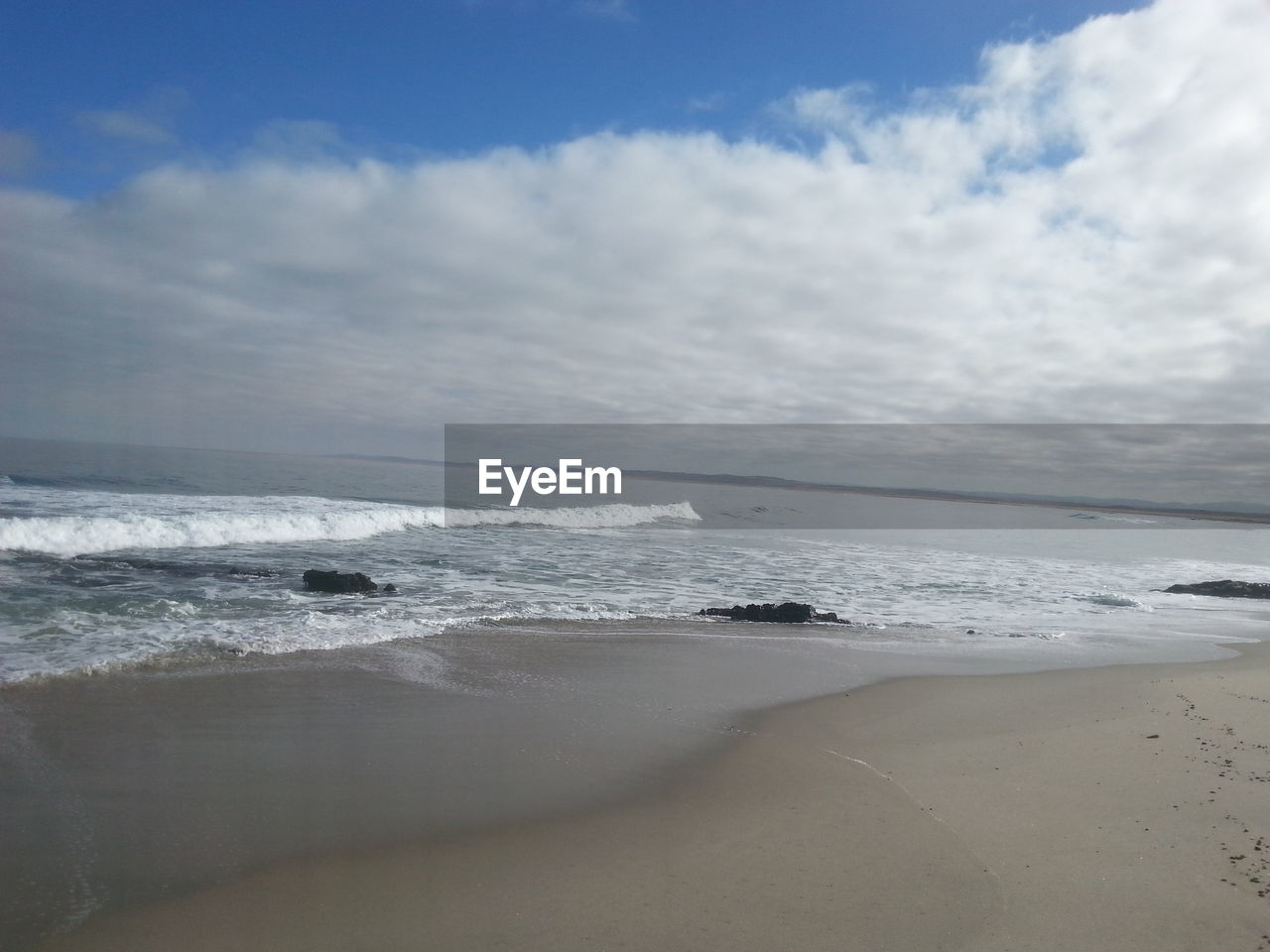 VIEW OF BEACH AGAINST CLOUDY SKY