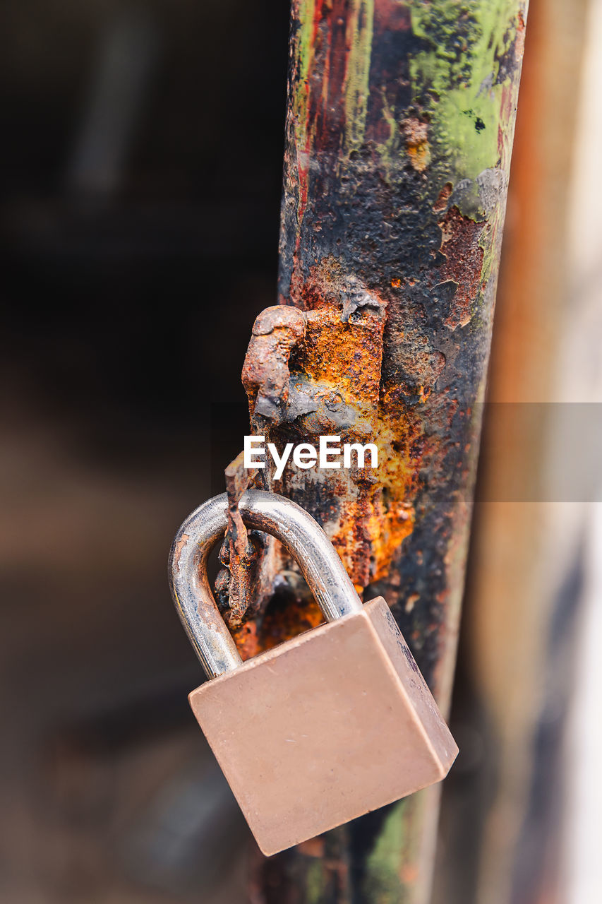 CLOSE-UP OF PADLOCK ON RUSTY METAL FENCE