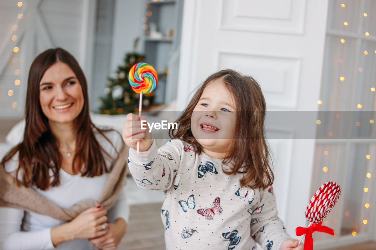 PORTRAIT OF A SMILING GIRL HOLDING CAMERA AT HOME