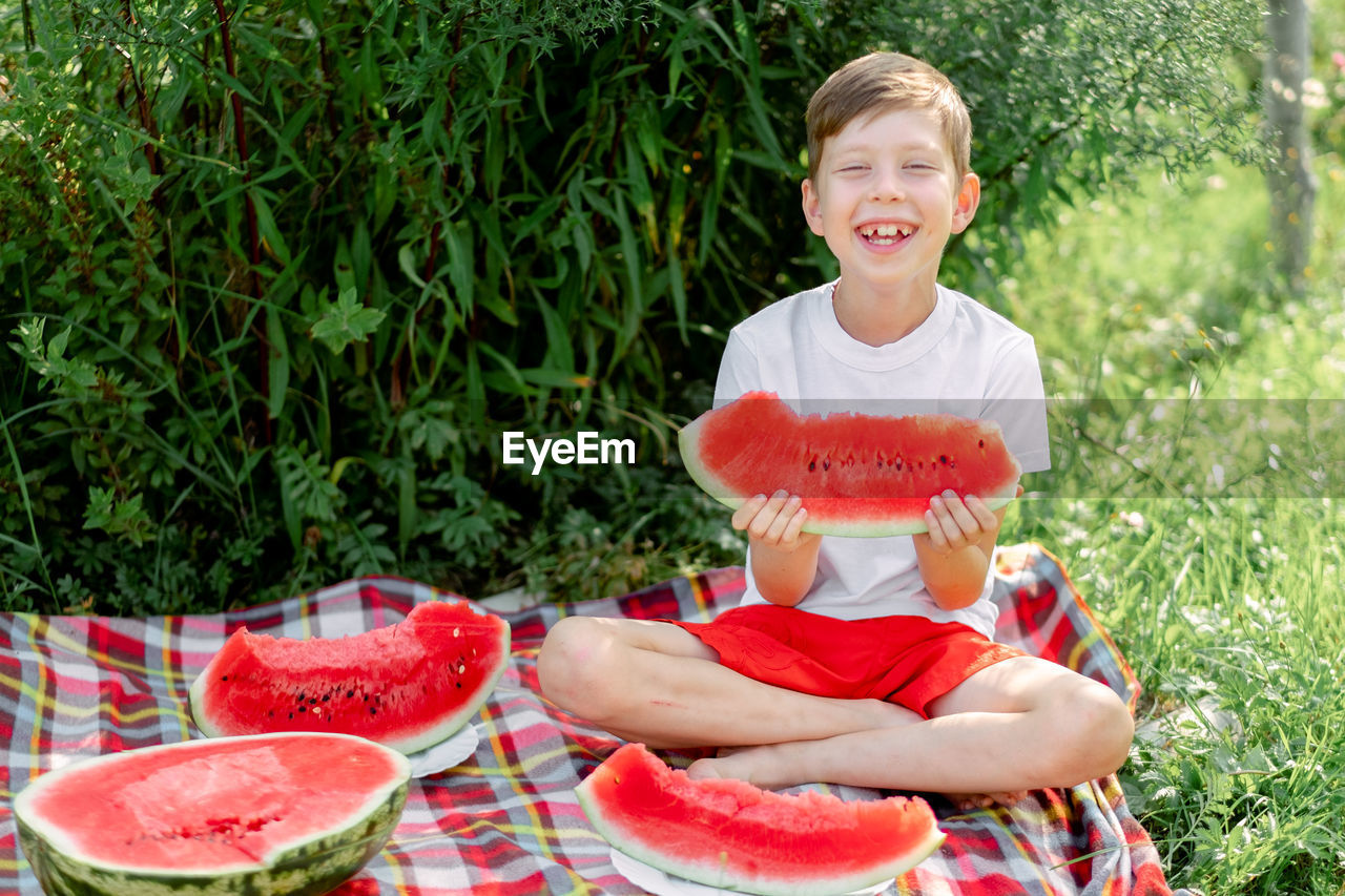 Boy eating watermelon white t-shirt. picnic with watermelons. 