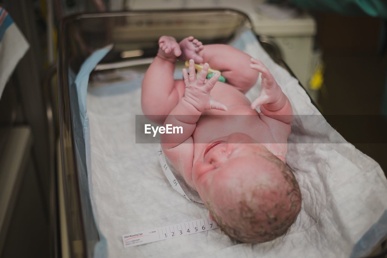 High angle view of cute naked baby lying in hospital