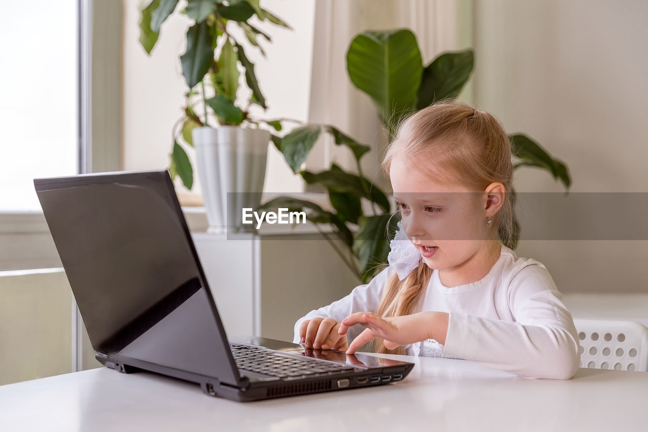 GIRL USING LAPTOP ON TABLE AT HOME