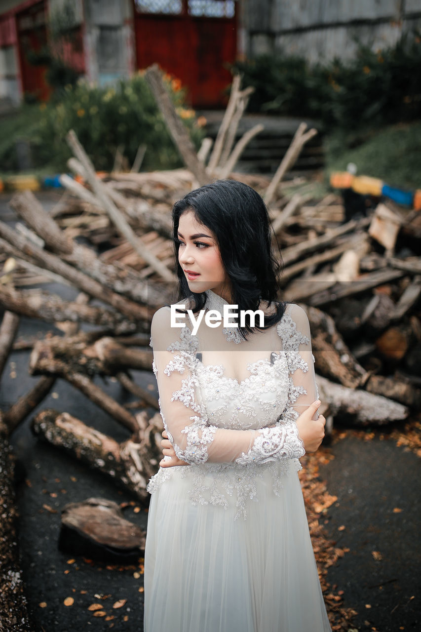 Portrait of young woman standing against tree trunk