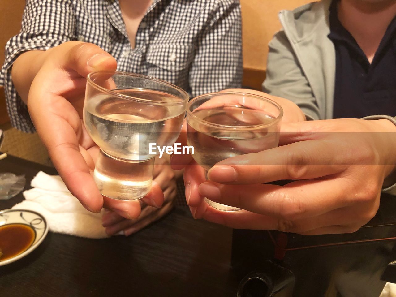 Midsection of people holding japanese sake glass for drinking in friday night. 