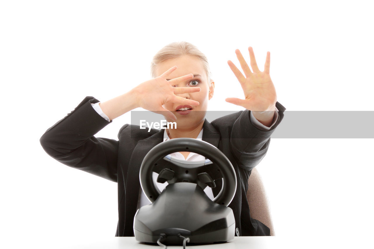 Businesswoman with toy steering wheel playing video game against white background