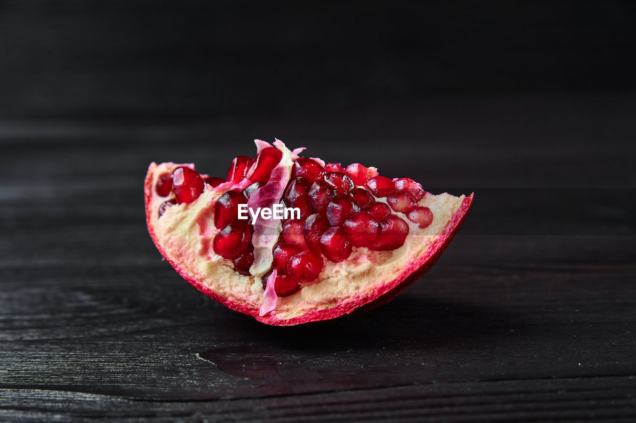 Red pomegranate on a black wooden background, food shot