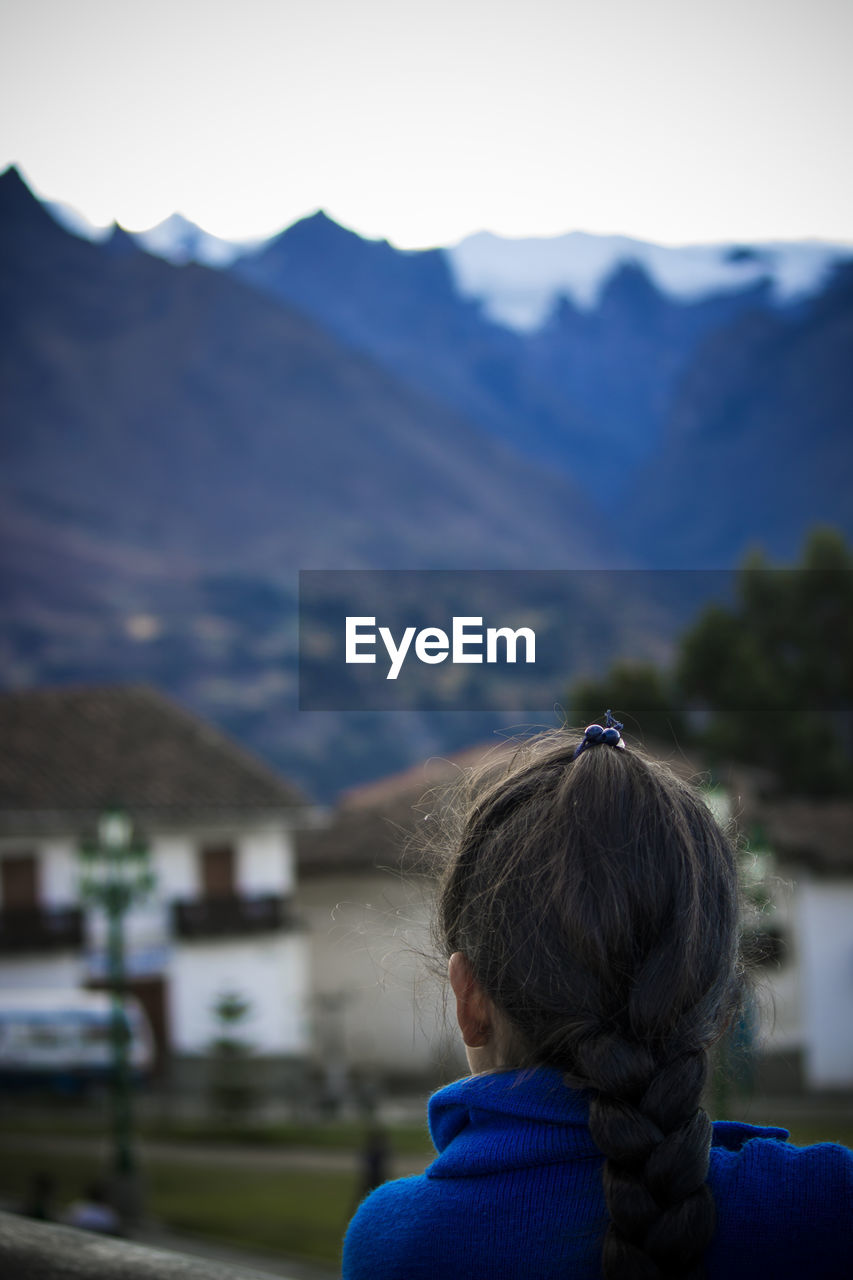 REAR VIEW PORTRAIT OF WOMAN AGAINST BUILDING