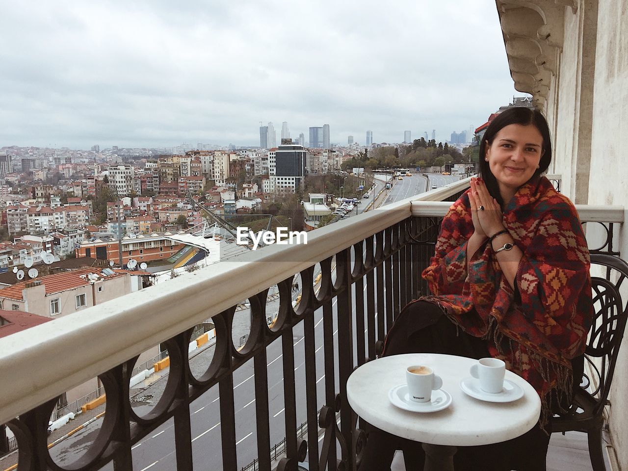 PORTRAIT OF SMILING WOMAN STANDING BY RAILING IN CITY