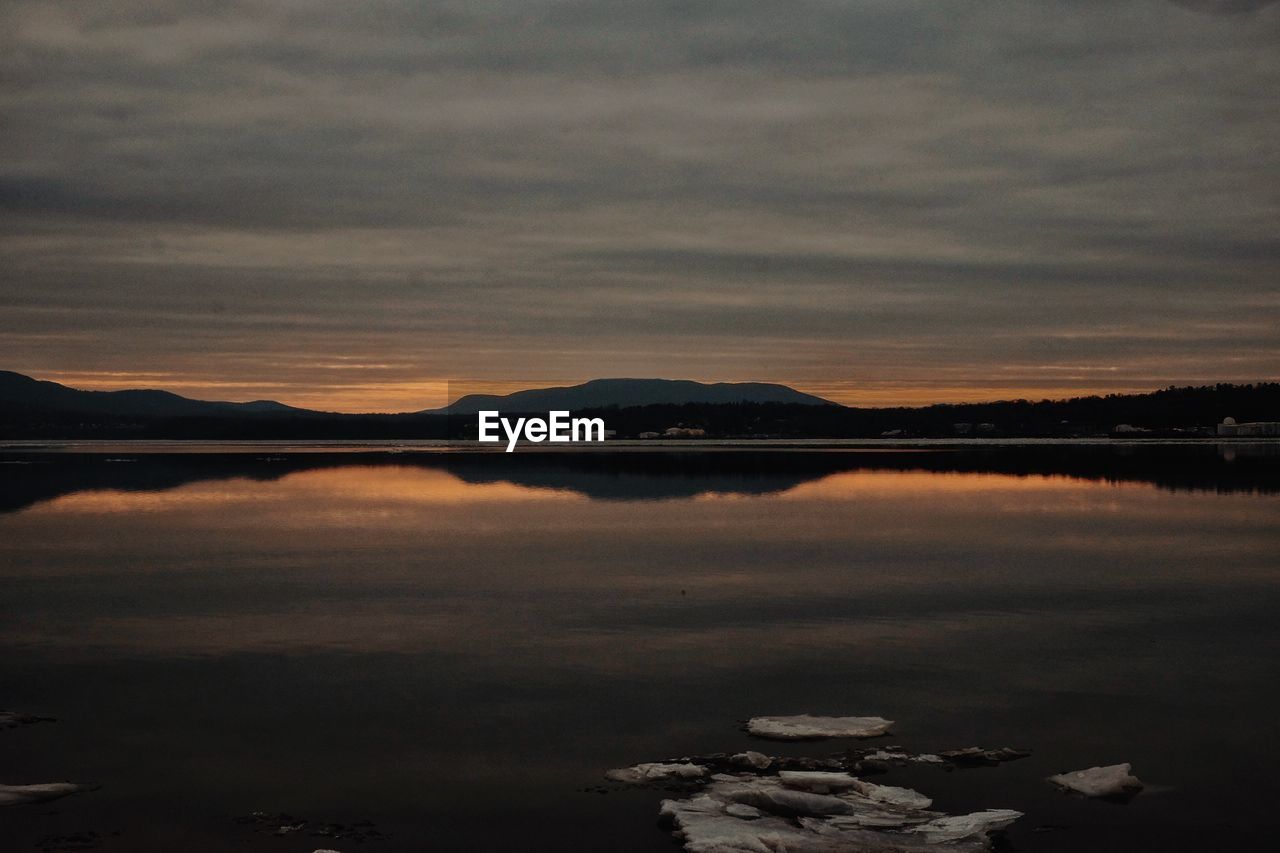 SCENIC VIEW OF LAKE BY SILHOUETTE MOUNTAINS AGAINST SKY