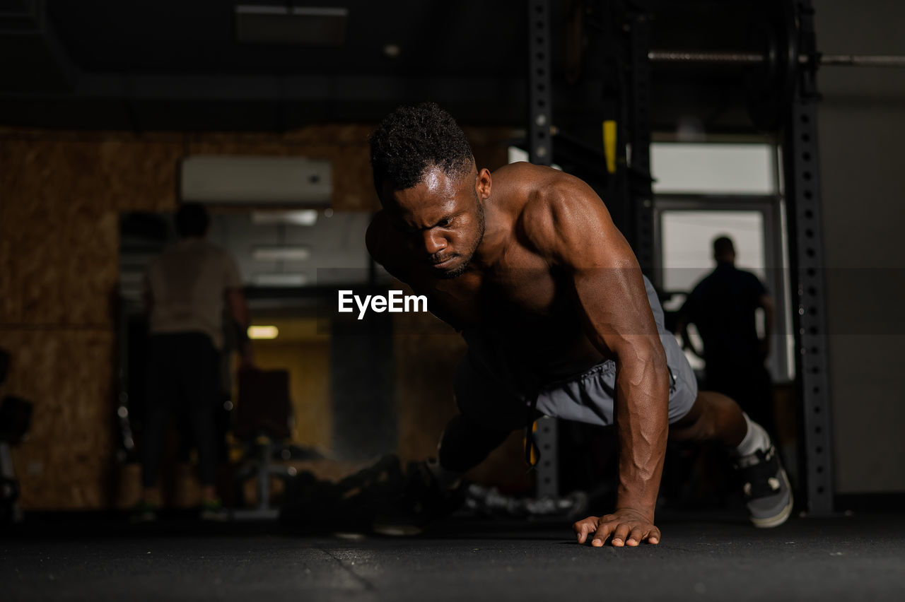 African american man doing one arm push ups in the gym. 