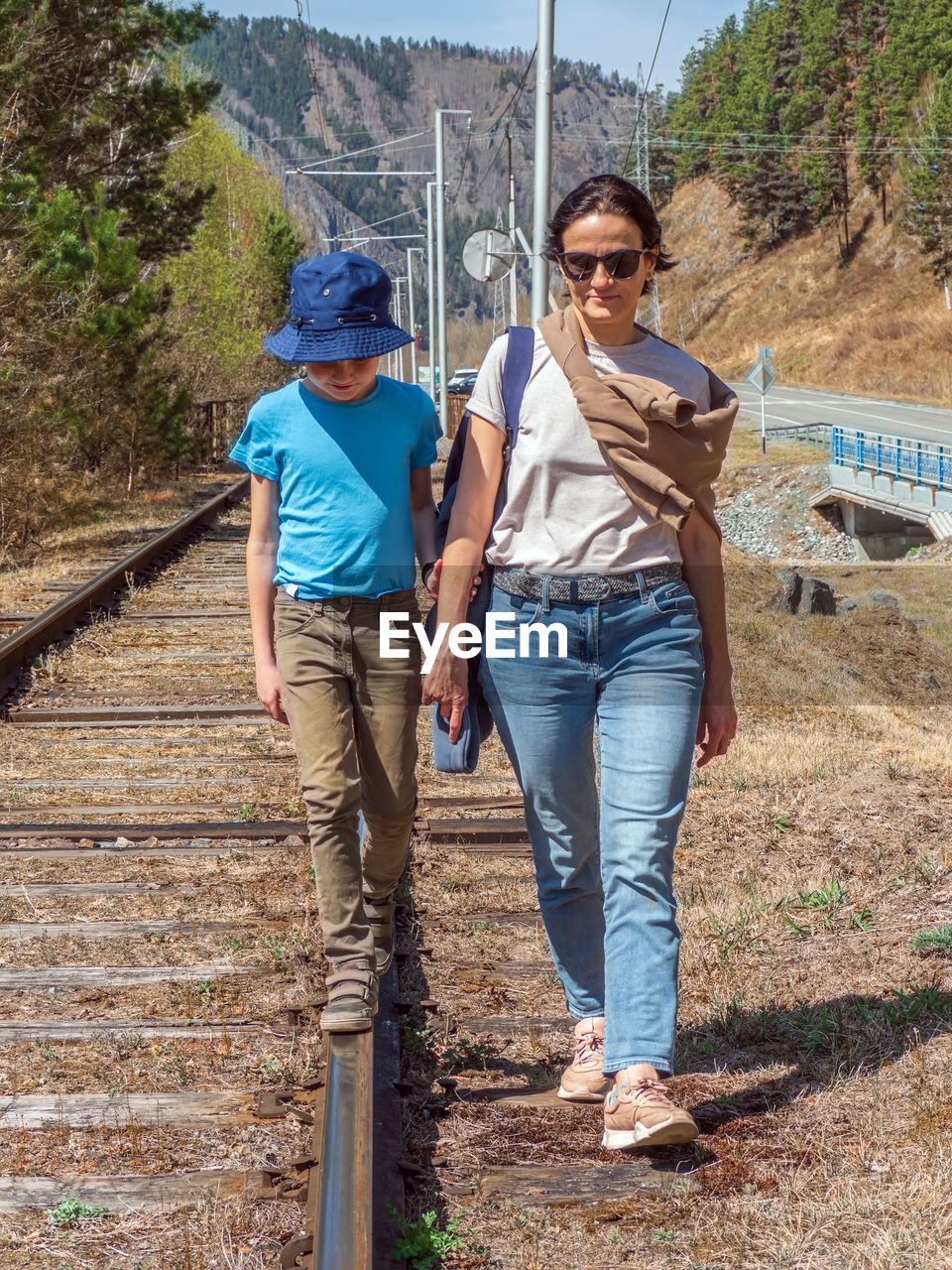 Mom and son walk along the old abandoned railway tracks.