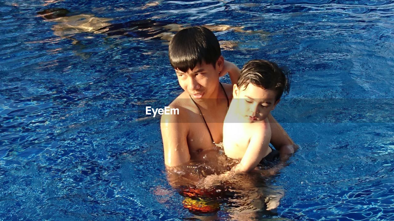 Shirtless teenage boy with brother in swimming pool