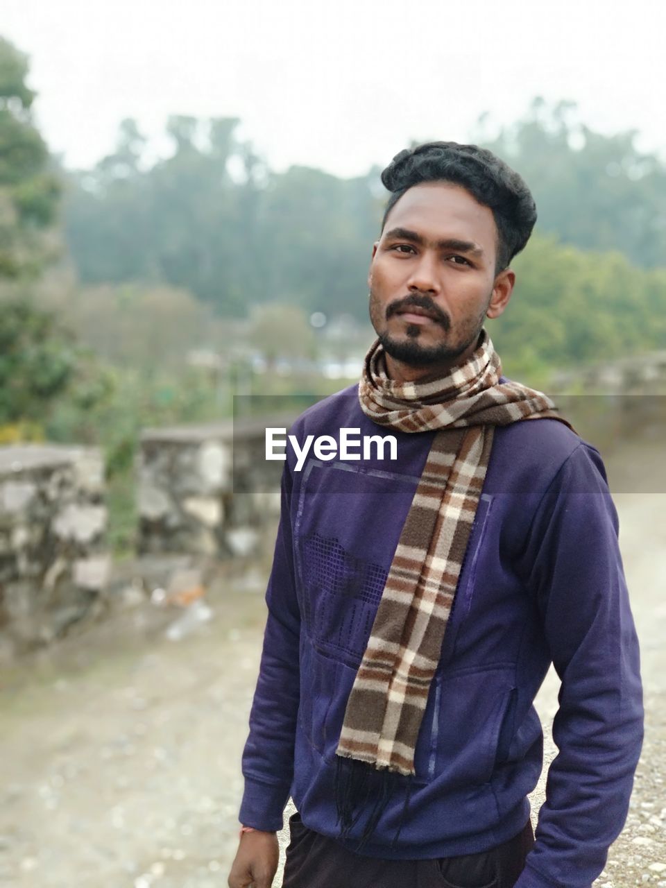 one person, adult, portrait, men, beard, standing, facial hair, young adult, looking at camera, nature, photo shoot, clothing, person, front view, waist up, spring, day, serious, sky, outdoors, casual clothing, focus on foreground, outerwear, looking, emotion, lifestyles, jacket, leisure activity, copy space, land, architecture, individuality, cool attitude, three quarter length, landscape, tree