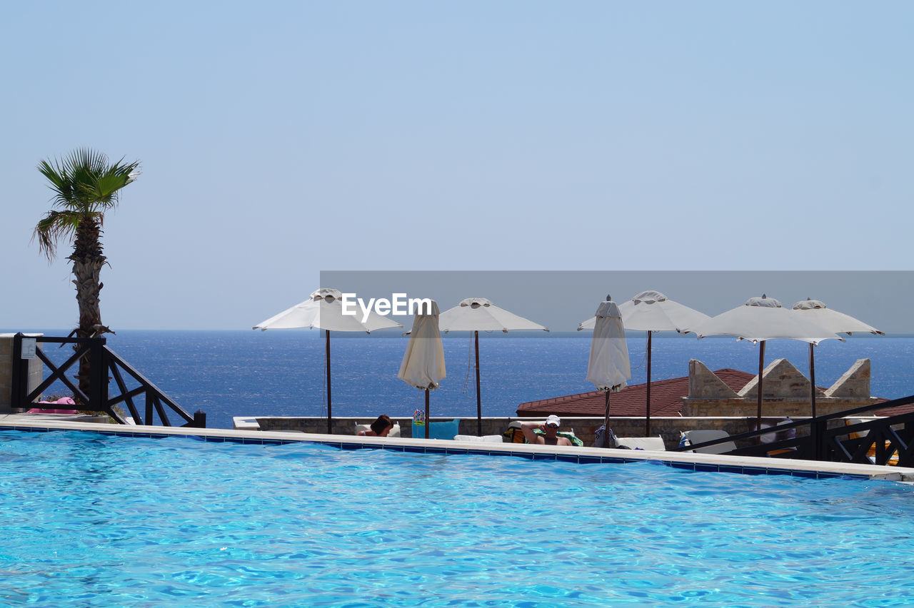 Swimming pool at tourist resort against clear sky