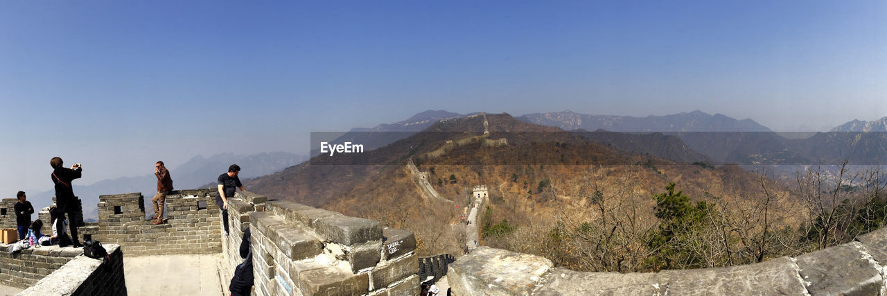 People standing on great wall of china against clear blue sky