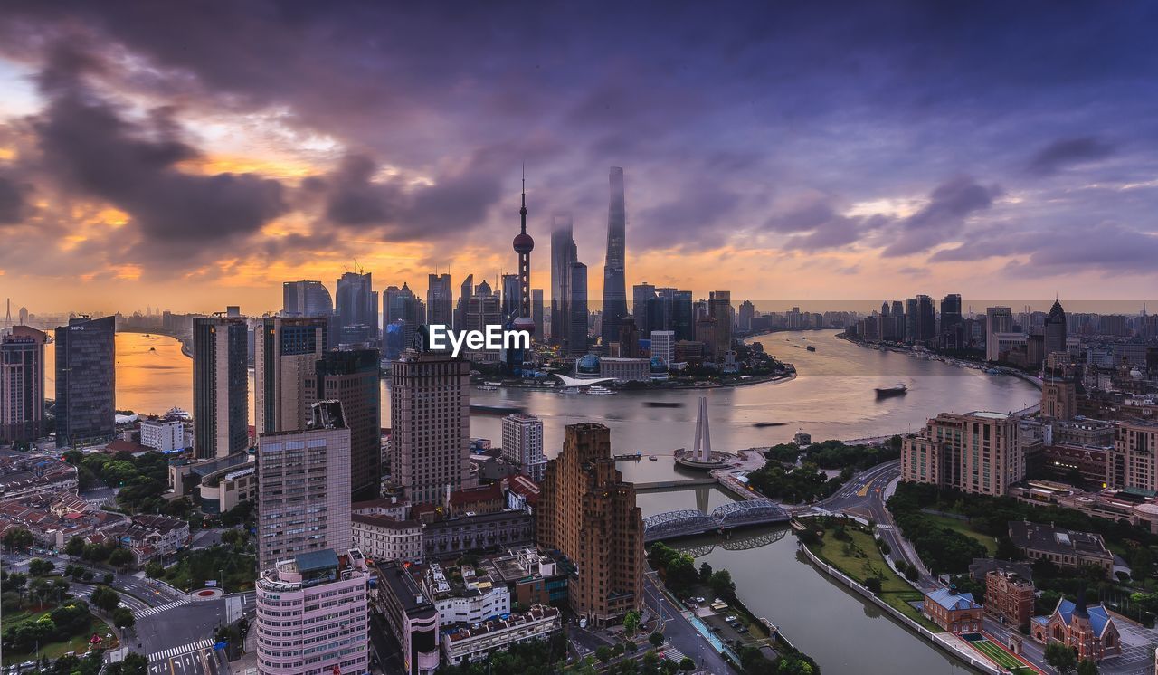 High angle view of cityscape and river against cloudy sky during sunset