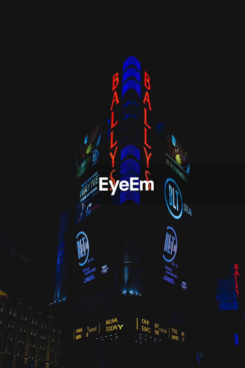 LOW ANGLE VIEW OF ILLUMINATED CLOCK TOWER AT NIGHT