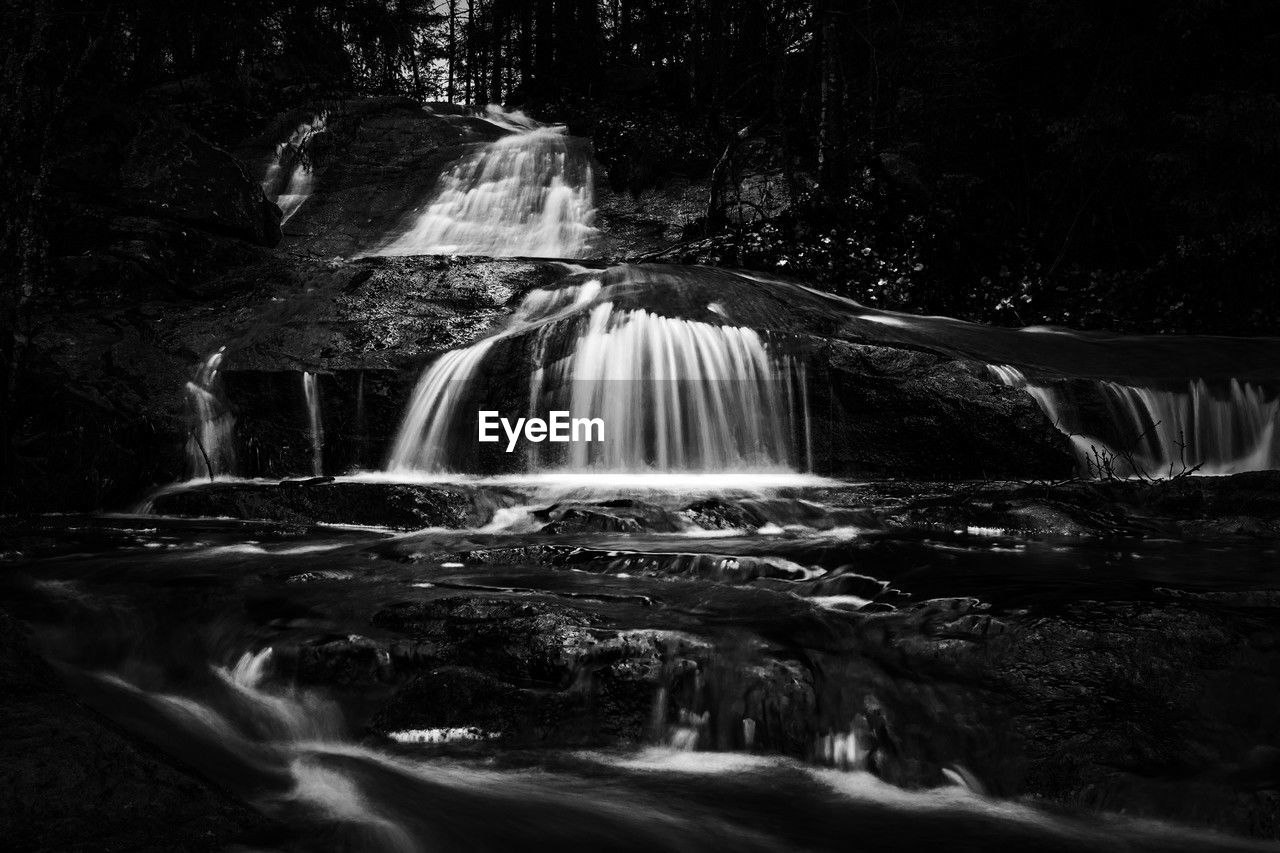 waterfall, water, black and white, scenics - nature, motion, darkness, monochrome photography, beauty in nature, long exposure, water feature, monochrome, nature, forest, environment, tree, land, flowing water, blurred motion, flowing, no people, plant, rock, outdoors, splashing, river, non-urban scene, speed, landscape, stream, travel destinations, black, body of water