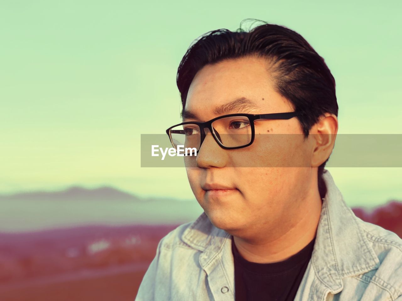 Close-up of man in eyeglasses against sky