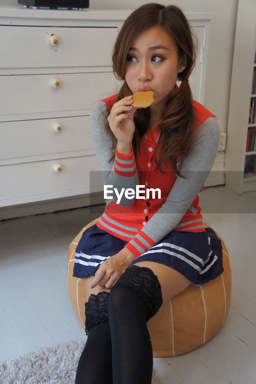 Young woman eating while sitting at home