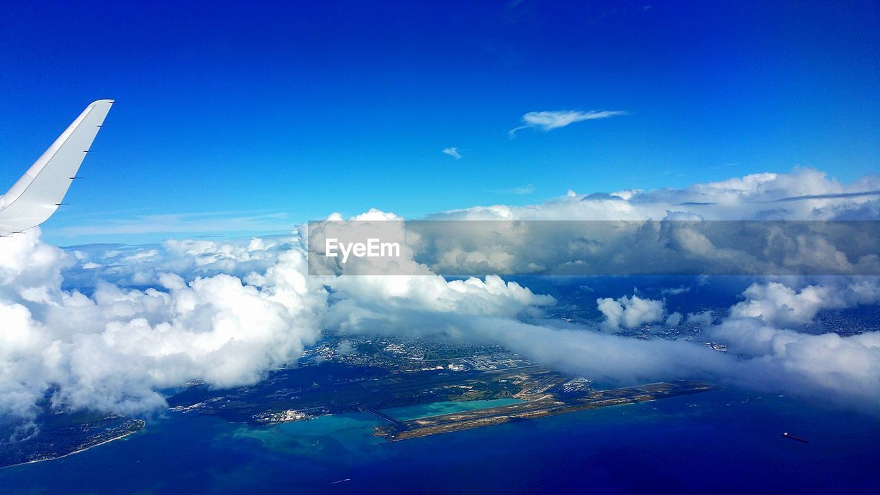 Cropped image of airplane flying over sea against blue sky