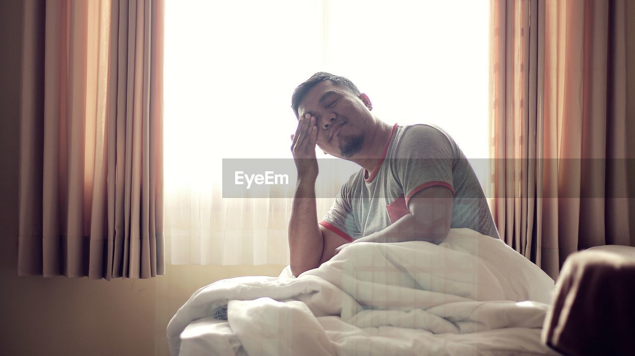 Portrait of man sitting on bed at home