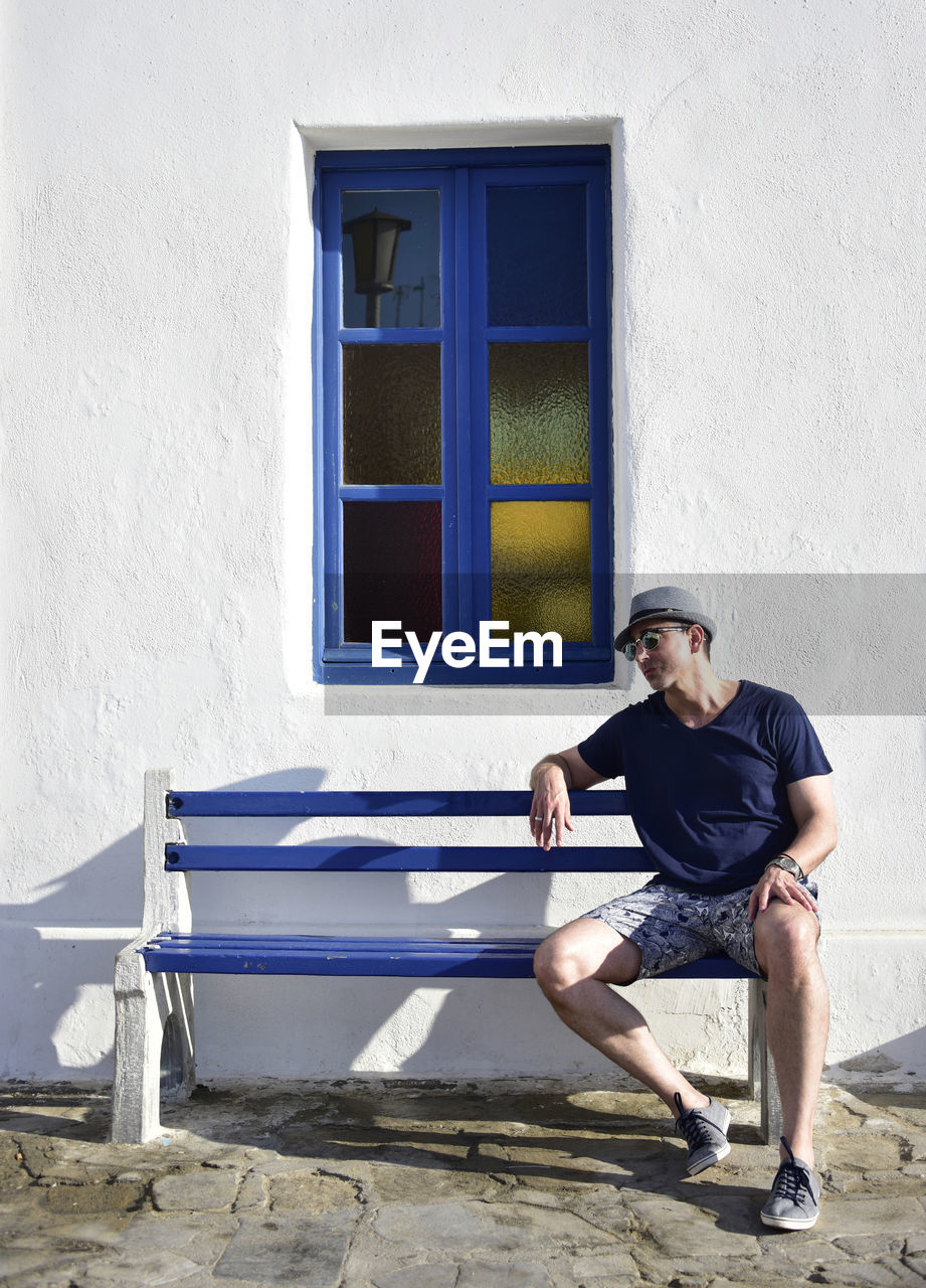 Tourist in mykonos on bench with window