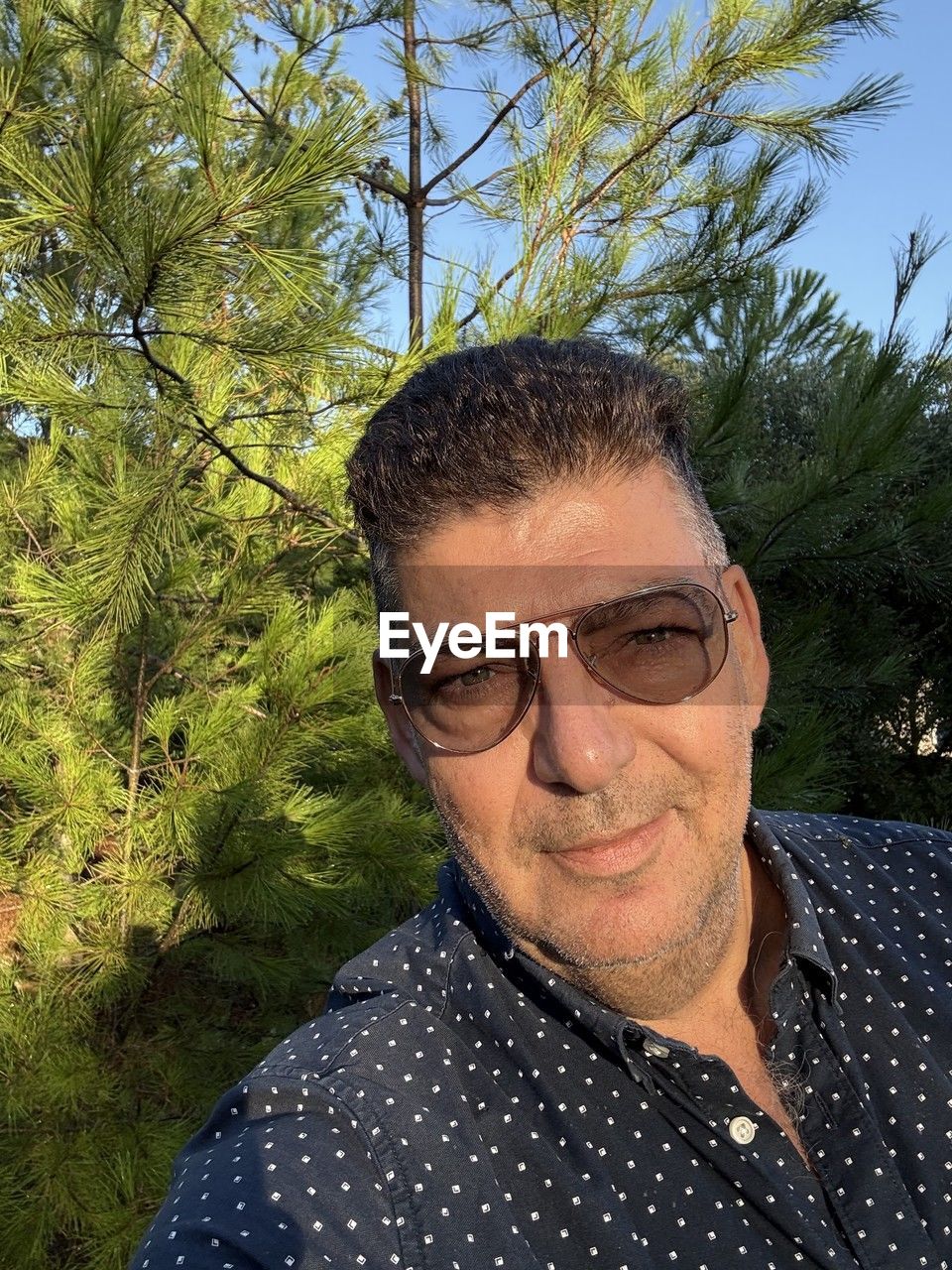 one person, plant, nature, adult, leisure activity, tree, lifestyles, men, day, portrait, smiling, headshot, lying down, outdoors, mature adult, relaxation, happiness, sunlight, eyes closed, beard, facial hair, holiday, casual clothing, sky, young adult