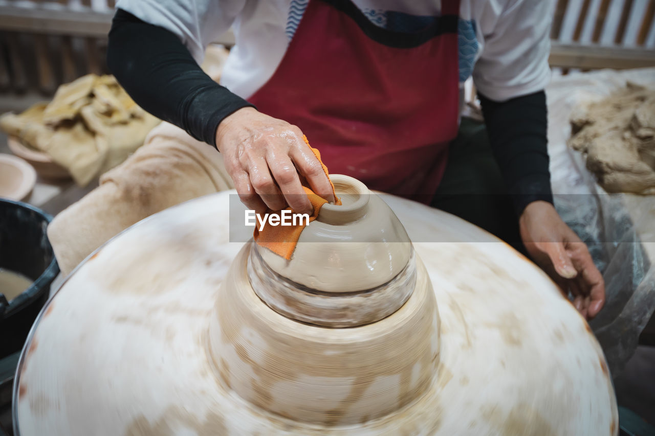 Midsection of potter working at workshop