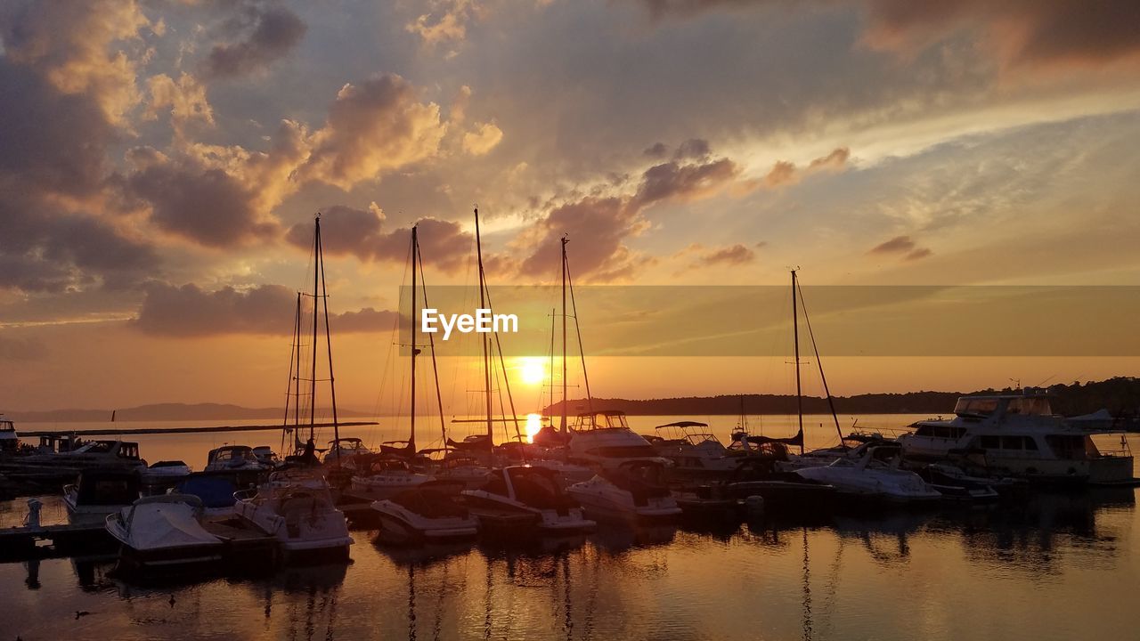 BOATS MOORED IN HARBOR AT SUNSET