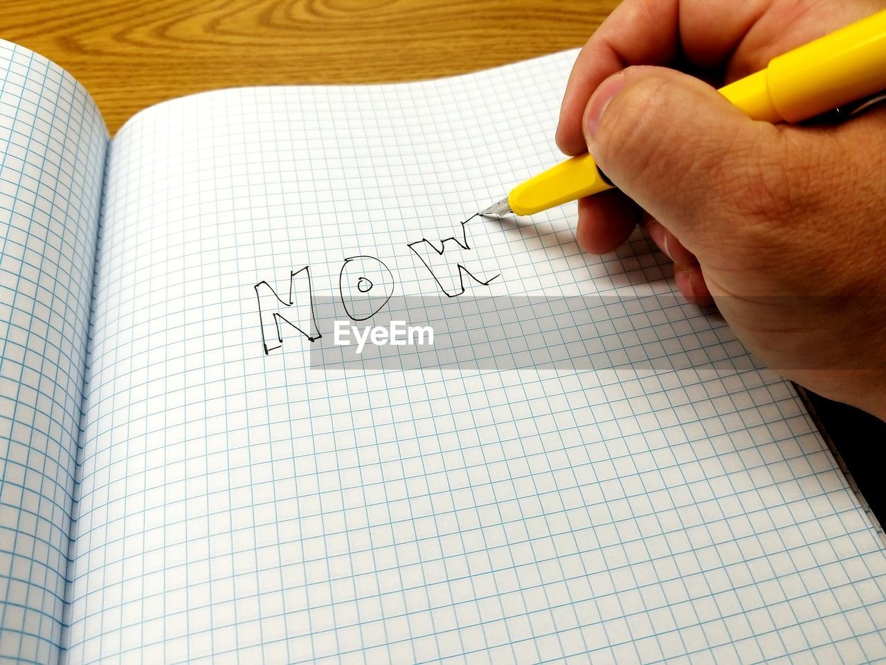 Cropped hand of man writing in book at table