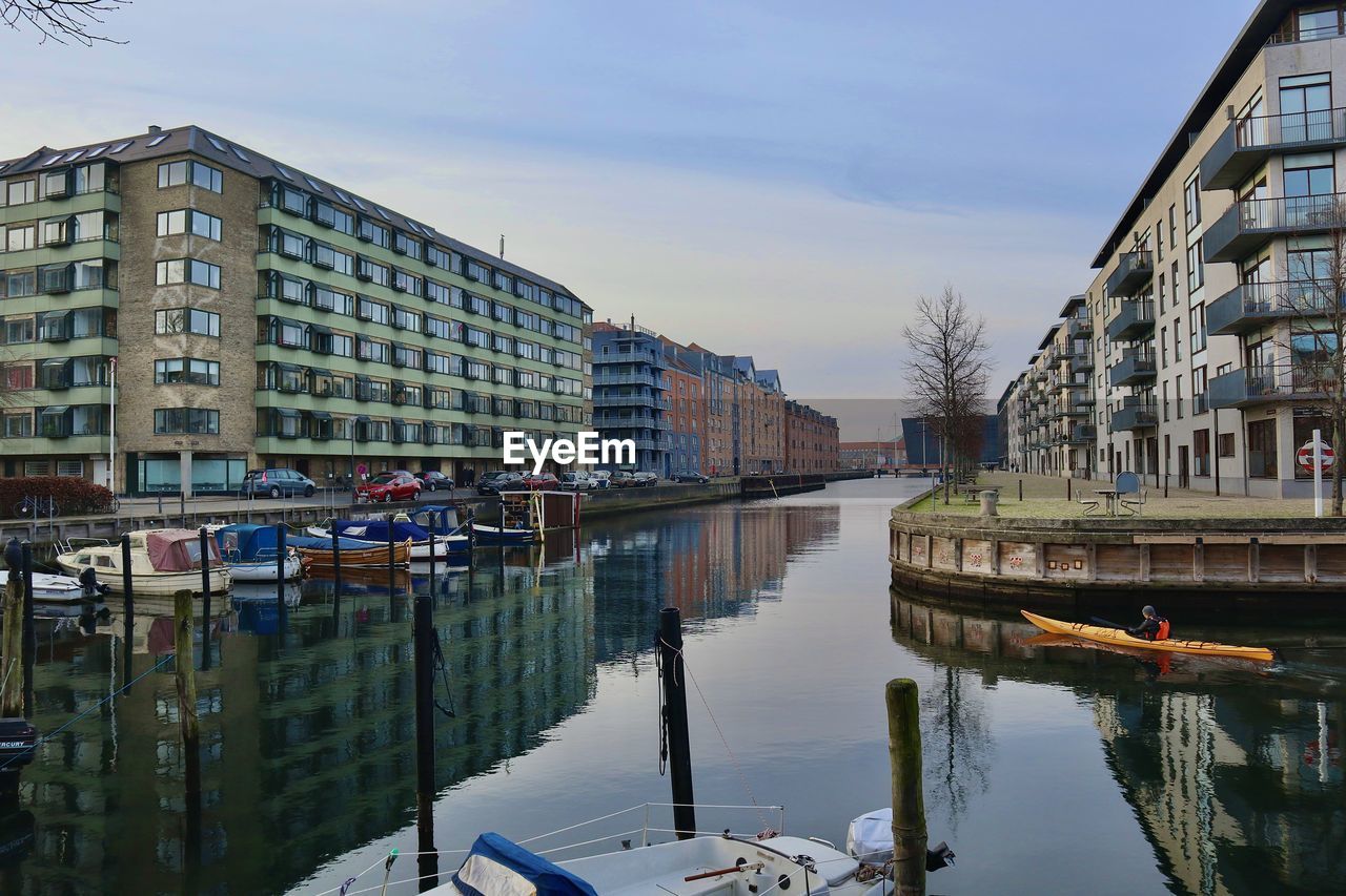 Canal amidst buildings in city against sky