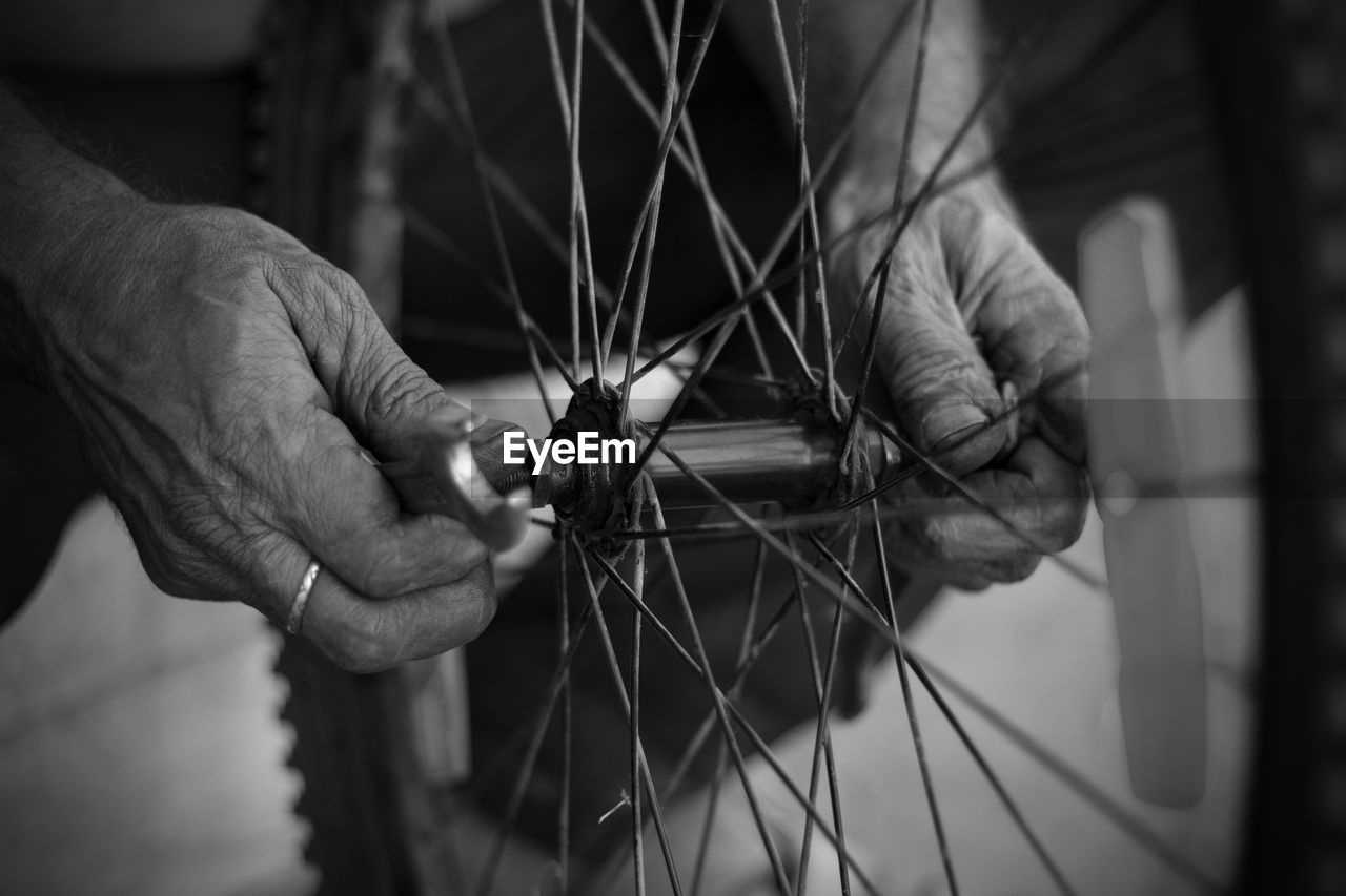 The old man working on motorcycle tire with tools close view in a service shop using finger in hands
