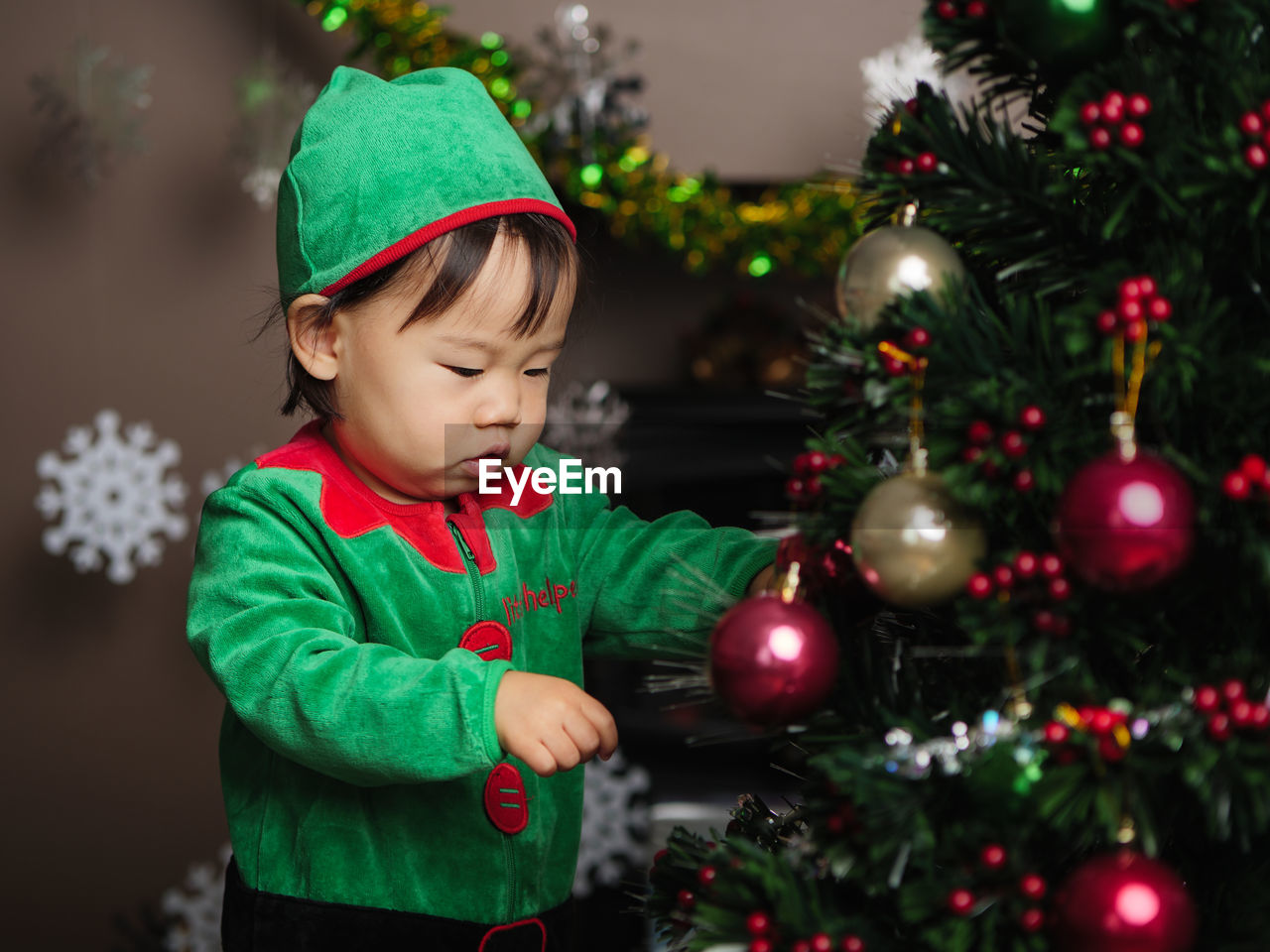 Cute girl wearing costume standing by christmas tree at home