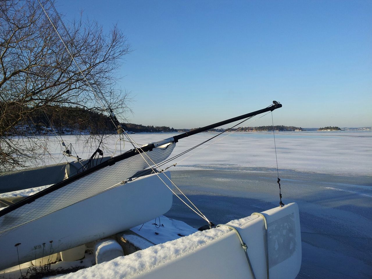 Cropped boat at frozen sea against clear blue sky