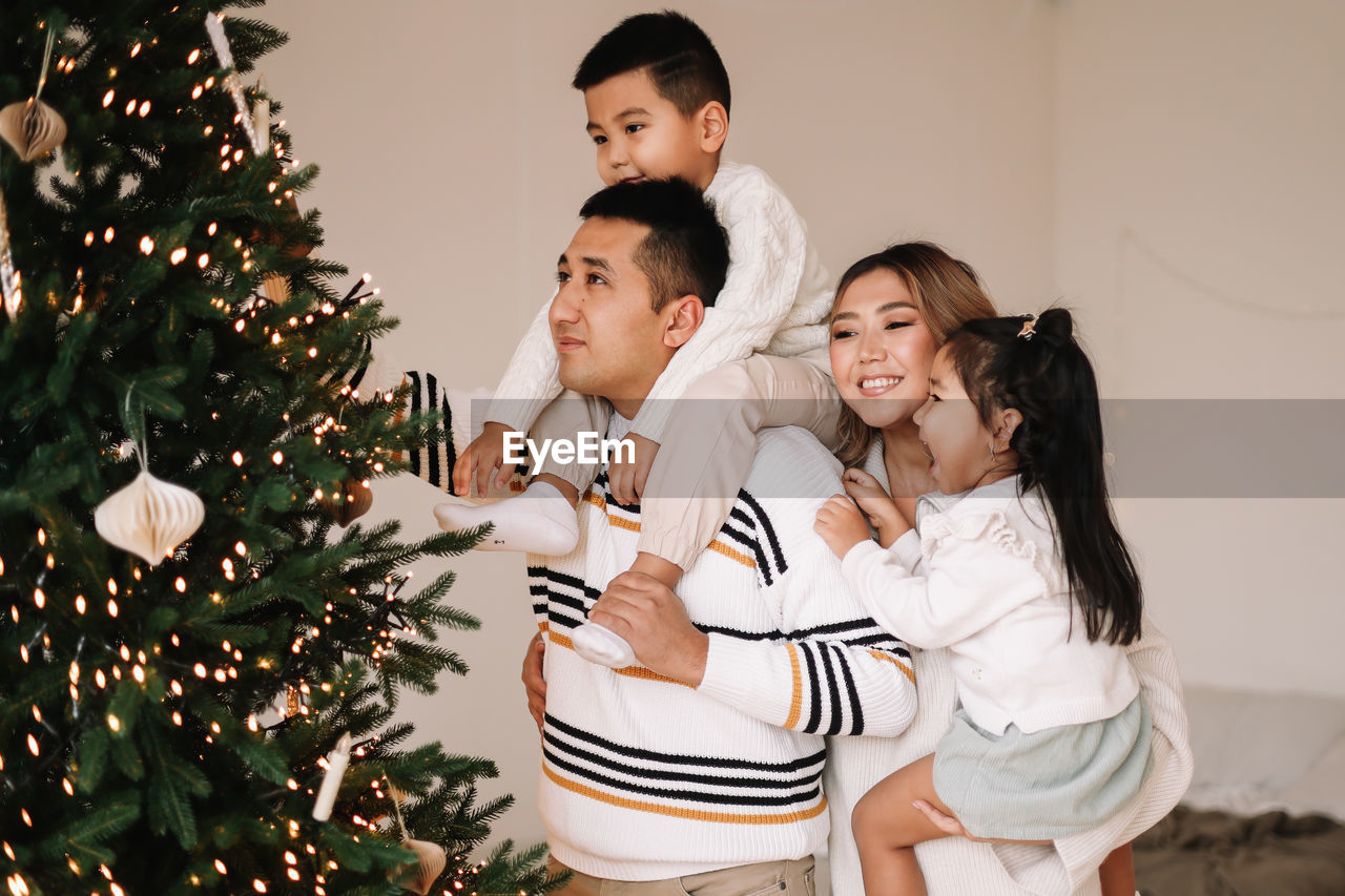 An asian multi-racial family with two children celebrate the christmas holiday in a decorated house