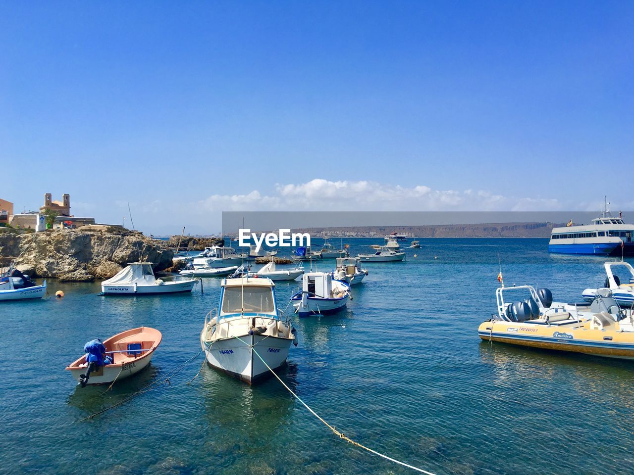 Boats moored in sea against blue sky