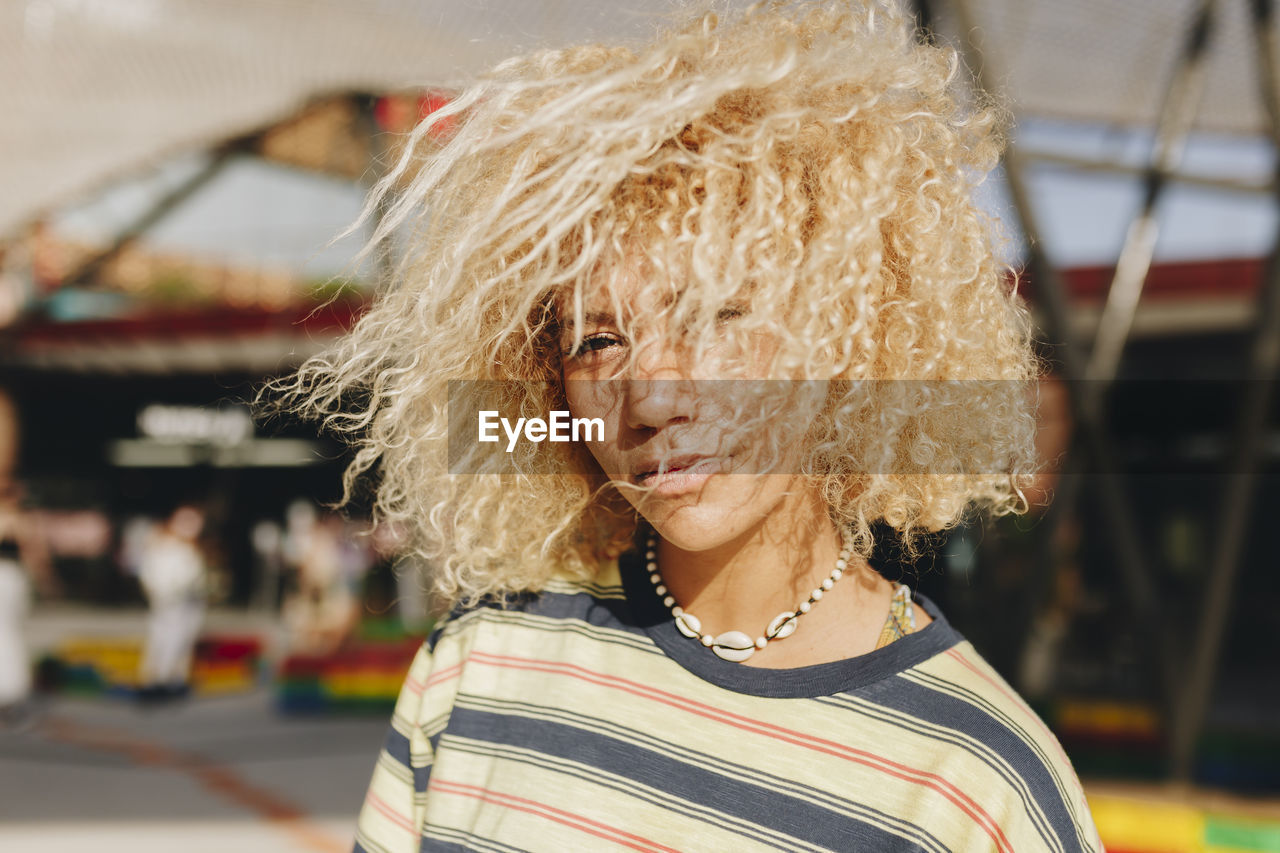 Confident blond afro woman standing outdoors on sunny day