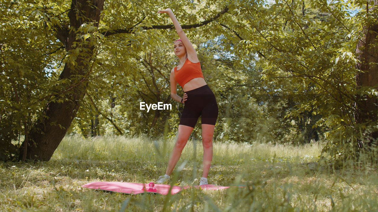 rear view of young woman exercising on field