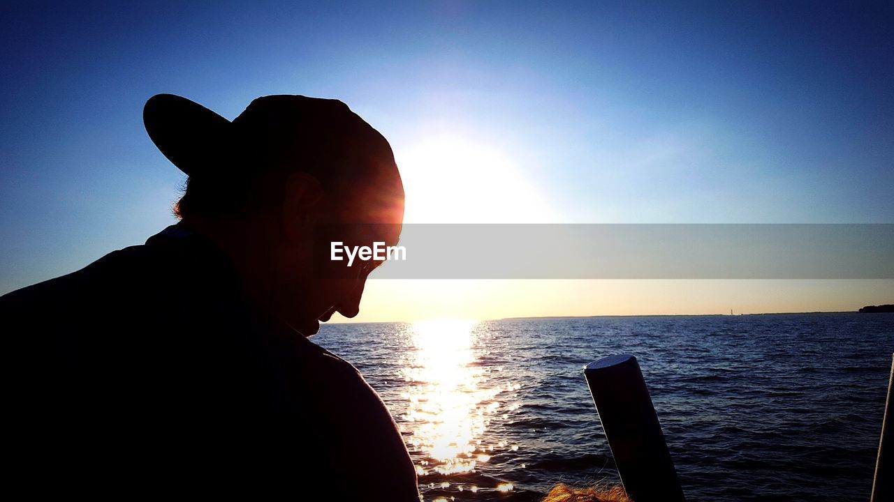 SILHOUETTE HAND AGAINST SEA DURING SUNSET