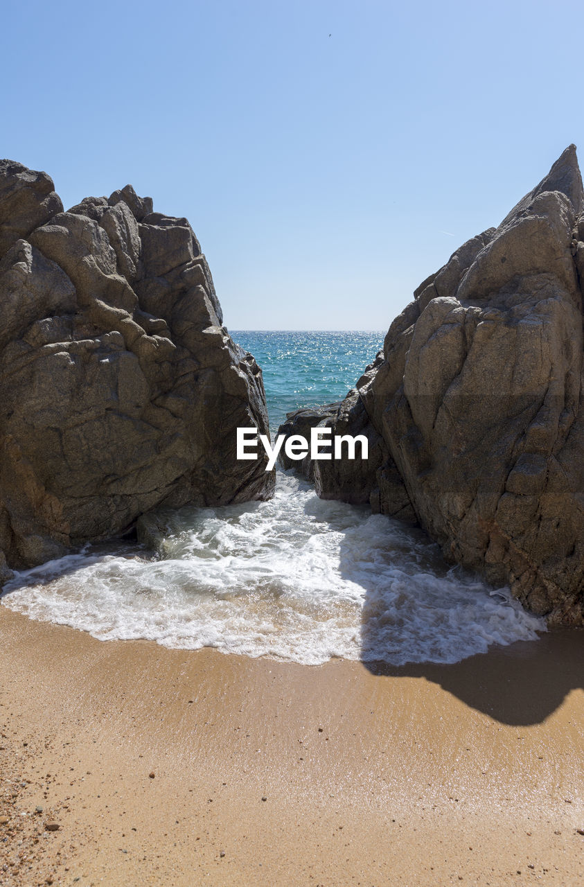 Rocks on beach against clear sky