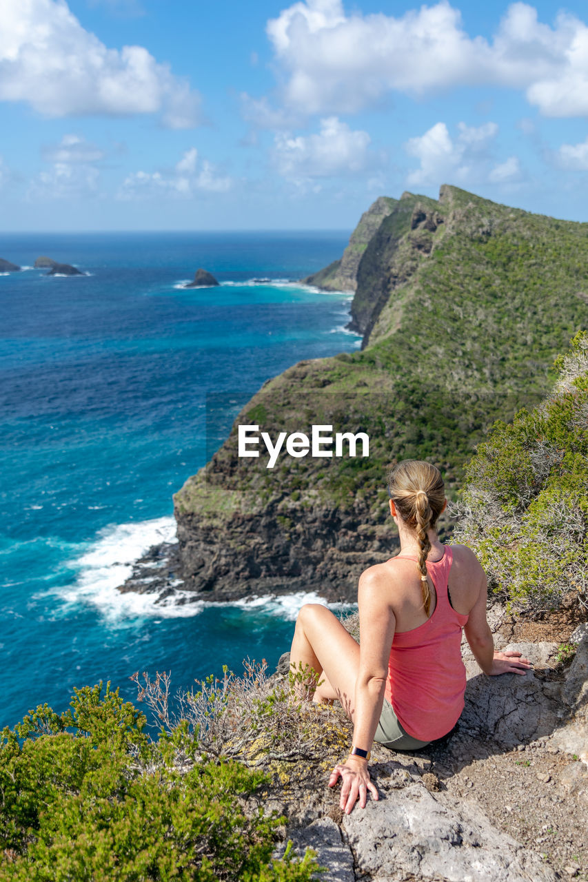 WOMAN LOOKING AT SEA AGAINST ROCKS