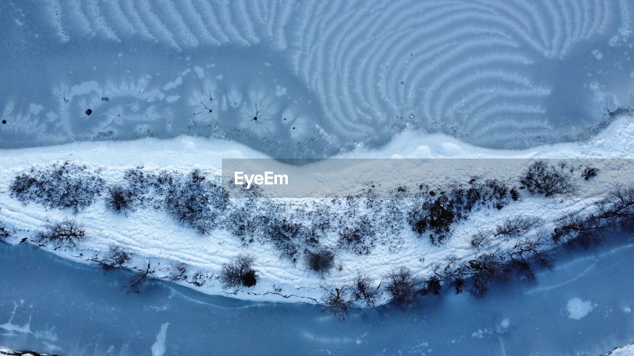 HIGH ANGLE VIEW OF SNOW COVERED LAND AND TREES