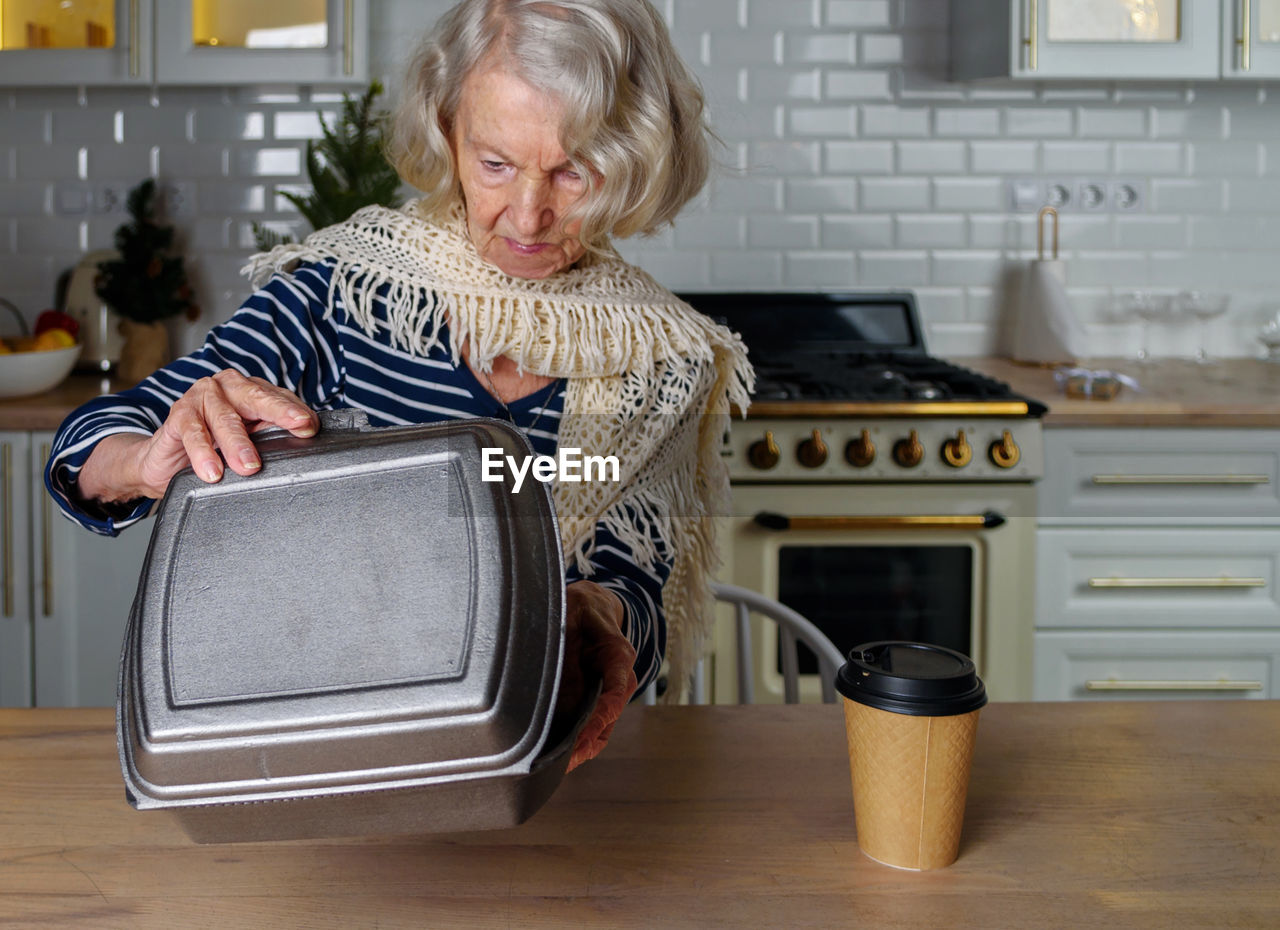 Lonely elderly woman opens food delivery from an online store