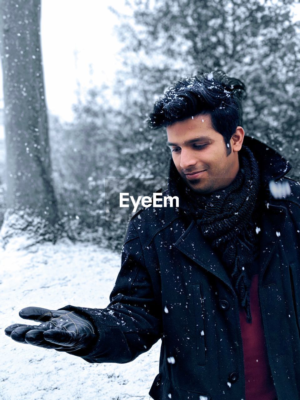 Smiling man standing outdoors during snow fall